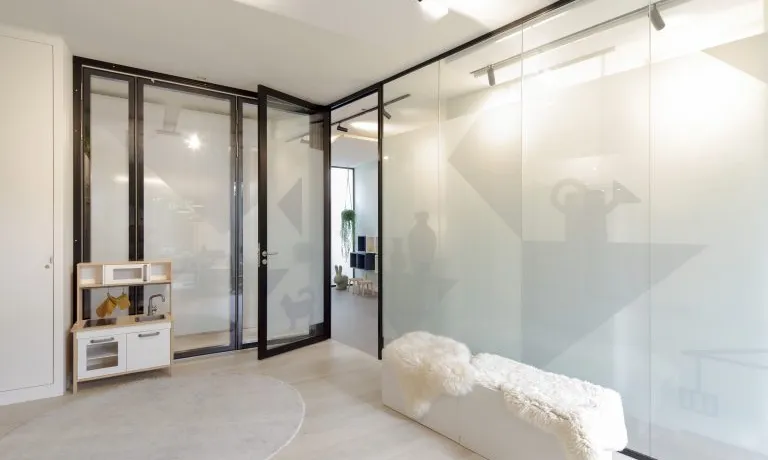 Wachtruimte met diagonale glaswand en speelhoek in logopediepraktijk Burger & Scheffer