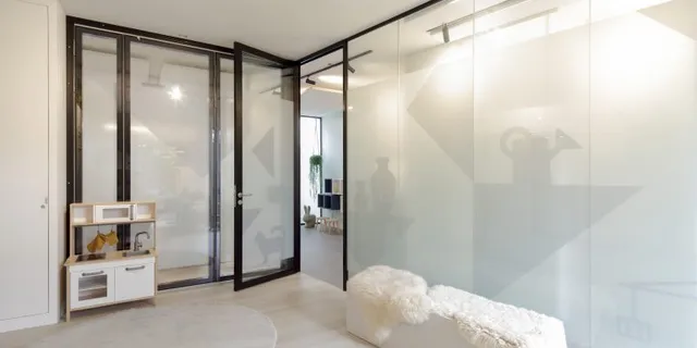 Wachtruimte met diagonale glaswand en speelhoek in logopediepraktijk Burger & Scheffer